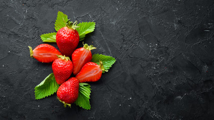 Fresh strawberry with leaves on a black stone background. Berries Top view. Free space for your text.