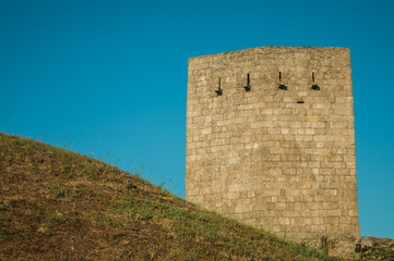 Naklejka premium Stone square tower over rocky hill on sunset