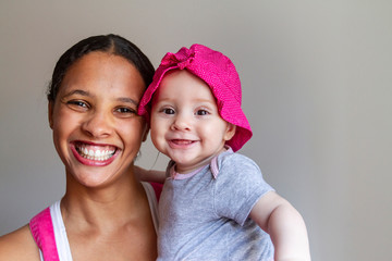 Black mother and her daughter white and redhead in contrast with neutral background