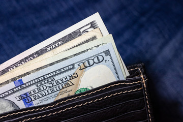 USA money, US DOLLAR, US Banknote inside black leather wallet on Jean Background.