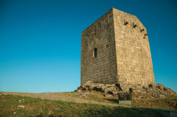 Stone square tower over rocky hill on sunset