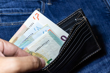 Euro money, Euro Banknote inside black leather wallet on Jean Background.