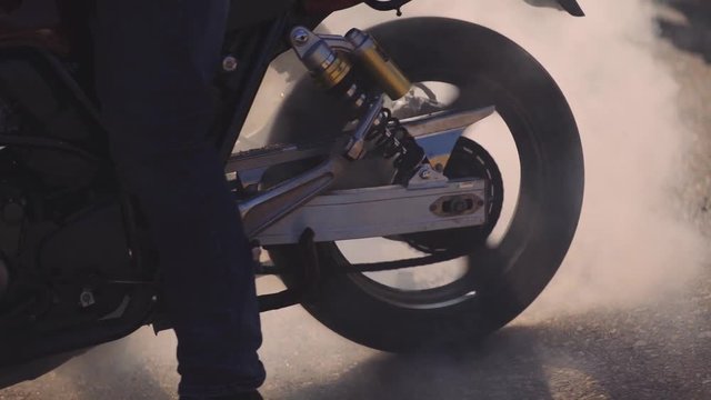 Motorcyclist doing tire burnout, slow motion. Professional motorcyclist drift and turns on a motorcycle on the asphalt, a biker does a trick on a motorcycle