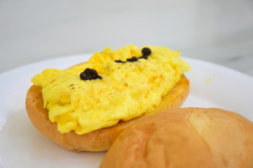 Scrambled eggs, black truffles, sauce, bun, closeup