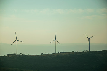 Hilly landscape with wind turbines on sunset