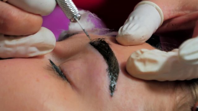 Close-up of cosmetologist making microblading procedure. Permanent makeup. Permanent tattooing of eyebrows. Cosmetologist applying permanent make up on eyebrows- eyebrow tattoo.