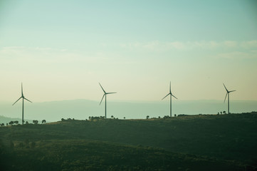 Fototapeta na wymiar Hilly landscape with wind turbines on sunset