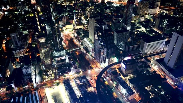 Top aerial view from tower rooftop, road junction traffic skyscrapers and busy evening highways night transition in modern downtown of Bangkok thailand.