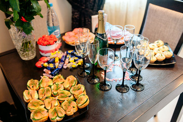 Candy bar. White wedding cake decorated by flowers standing of festive table with deserts, strawberry tartlet and cupcakes. Wedding. Reception Tartlets