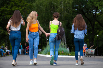 Obraz premium Happy women in blue jeans walking in summer park