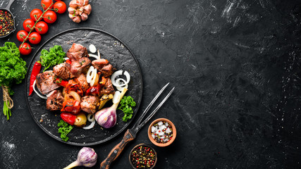 Kebab in a plate. Baked meat with onions and tomatoes. Barbecue. Top view. Free space for your text. Rustic style. - obrazy, fototapety, plakaty