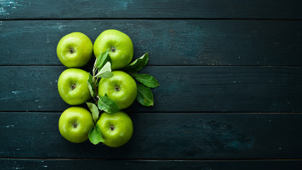 Fresh green apples with green leaves on a black background. Fruits. Top view. Free space for text.