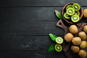 Fresh kiwi and green leaves on the table. Rustic style. Fruits. Top view. Free space for text. - obrazy, fototapety, plakaty