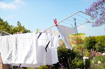 Rack dryer standing on the terrace on sunny day for drying white clothes. Collapsible clotheshorse...