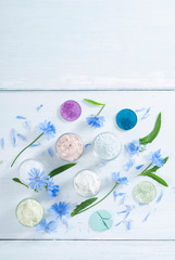 moisturizers, bath salts and powder compacts with blue chicory flowers on white wood table