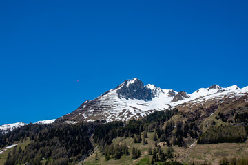 Panorama from the Davos lake -Switzerland with high partial snowy mountains of the Alps in spring at sunshine and blue sky