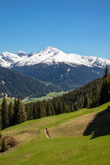 Panorama of high partly snowy mountains at blue sky taken from the Schatzalm-Davos in the swiss alps