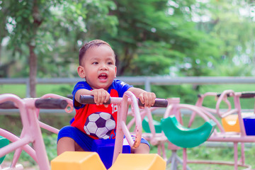 Fototapeta na wymiar Carousel in the park for children. asian little boy playing on playground