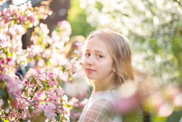 candid portrait of a girl in a blooming apple orchard