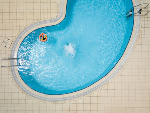 Aerial drone picture about a beautiful, blue ,outdoor swimming pool with playing children.