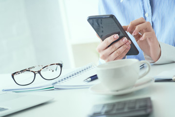 Close up of hand of businesswoman using smartphone at office. Business, technology and people concept.