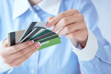 Woman hand holding various credit cards and making choice with another hand close-up.