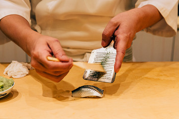 Japanese Omakase Menu: Saba Sushi (Mackerel) brush minced Yuzu peel with steel peel scraper. Japanese traditional and luxury meal.