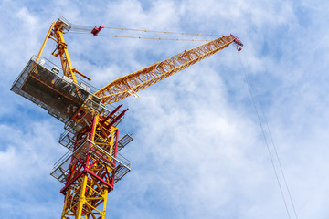 Naklejka premium Crane working in construction site with cloud and blue sky in background.