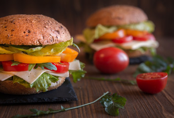 Delicious andwiches with cheese, lettuce, vegetables and arugola on dark background