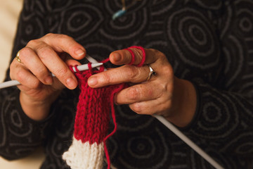 Hands of a lady knitting scarf at home