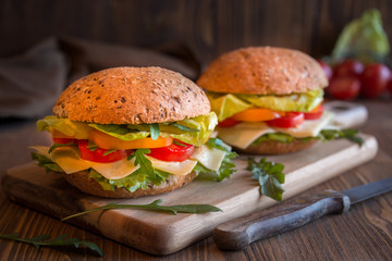 Delicious andwiches with cheese, lettuce, vegetables and arugola on dark background