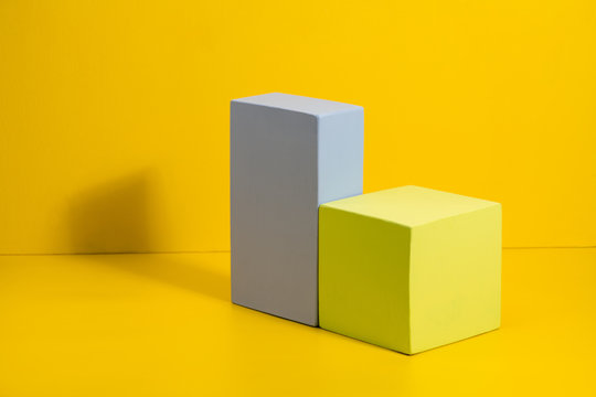 Geometric shapes in different colors on yellow background. Three-dimensional solid figures on colored paper.
