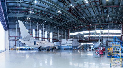 Passenger aircrafts under maintenance. Checking mechanical systems for flight operations. Panorama of airplanes in the hangar - obrazy, fototapety, plakaty