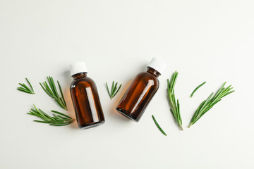 Flat lay composition with rosemary oil and leaves on white background, space for text