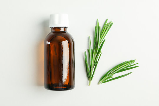 Flat lay composition with rosemary oil and leaves on white background, space for text