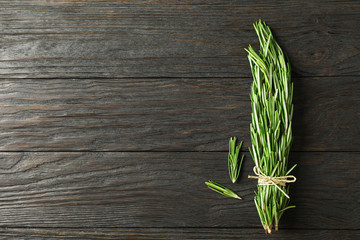 Green rosemary on wooden table, space for text