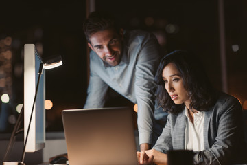 Office colleagues working on a laptop late at night
