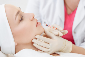 Obraz na płótnie Canvas Close-up master cosmetologist makes injection of hiluronic acid in the face of a beautiful young woman. The concept of modern anti-aging procedures in the beauty salon