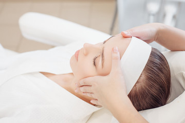 Unknown masseuse beautician doing a face massage to her client a beautiful young woman. Skin care...