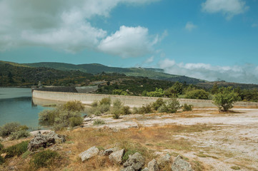 Rocky shore next to the concrete dam of Rossim Lake