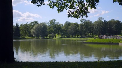 Tourists walk on a shore of a Great Pond in Alexandrovsky Park , feed ducks