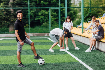 Full length view of athletic african american soccer player  staying with ball on green field.