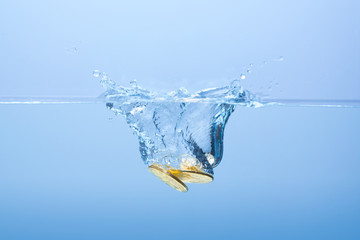 Coins in the water. Water splash from falling gold coins. Golden coins falling in water with...