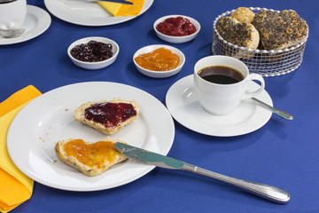 breakfast table with freshly baked heart shaped buns, different jams and coffee