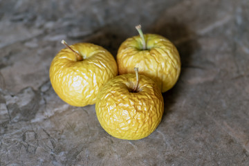 Wrinkled yellow old apples lies on the table top.