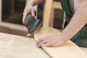 Young american european guy carpenter is working on the design of a new unique wooden furniture in his workshop. Concepts of own production