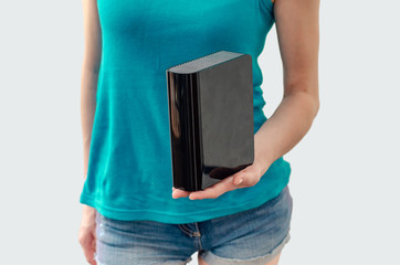 Young woman holds in her hand a black external hard drive