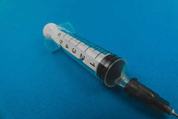 medical syringe with a needle lying on a blue background