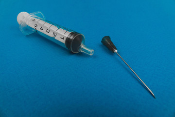 medical syringe with a needle lying on a blue background