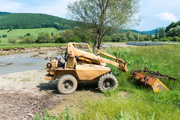 Obraz premium Abandoned ,old mini excavator near a small river.